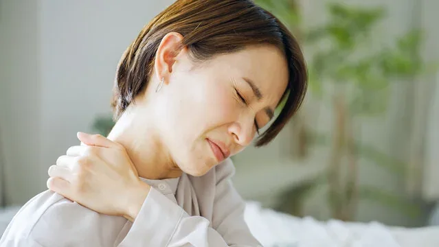 肩に手を当てて痛がる女性